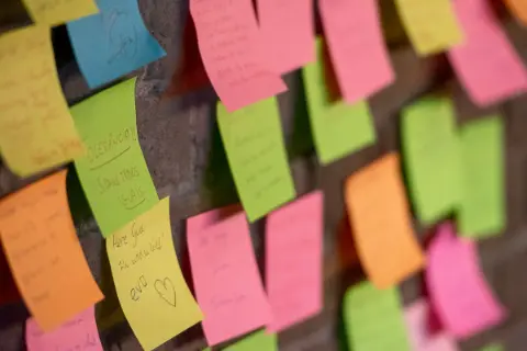A hand arranging sticky notes on a wall