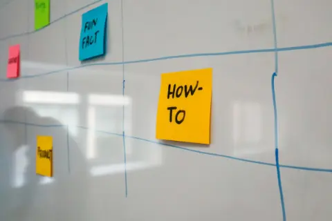 Colorful sticky notes taped to a schedule on a whiteboard