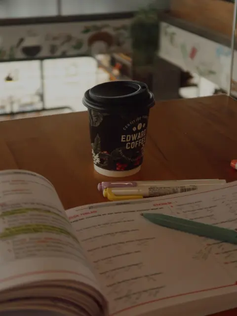 A coffee cup beside an open book on a desk
