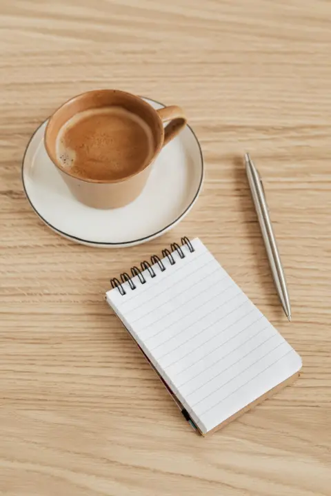 A cup of coffee and an open notebook with a pen