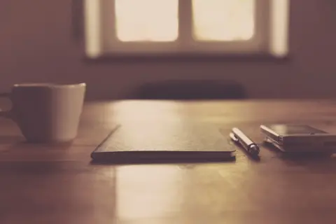 A minimalist desk with a notebook, pen and smartphone